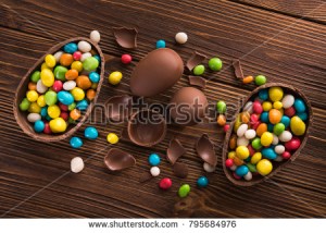 stock-photo-easter-dessert-tasty-chocolate-egg-with-color-candy-dragee-on-wooden-table-795684976